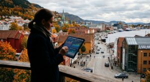 A professional editorial photograph of a business district in a small Norwegian city during autumn,