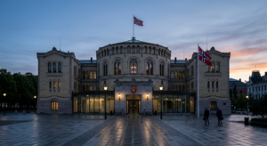 A professional editorial photograph of the Norwegian Parliament building in Oslo at dawn, featuring